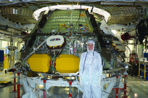 Heather McKay stands in front of the Exploration Flight Test-1 (EFT-1) Crew Module in the clean room at Kennedy Space Center. All personnel in the clean room wear ?bunny suits? to prevent foreign objects and debris from contaminating the spacecraft.
