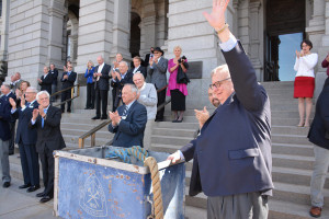 President Scoggins, standing with the Ore Cart, waves to the crowd from the steps of the Capitol building. (Kathleen Morton) 