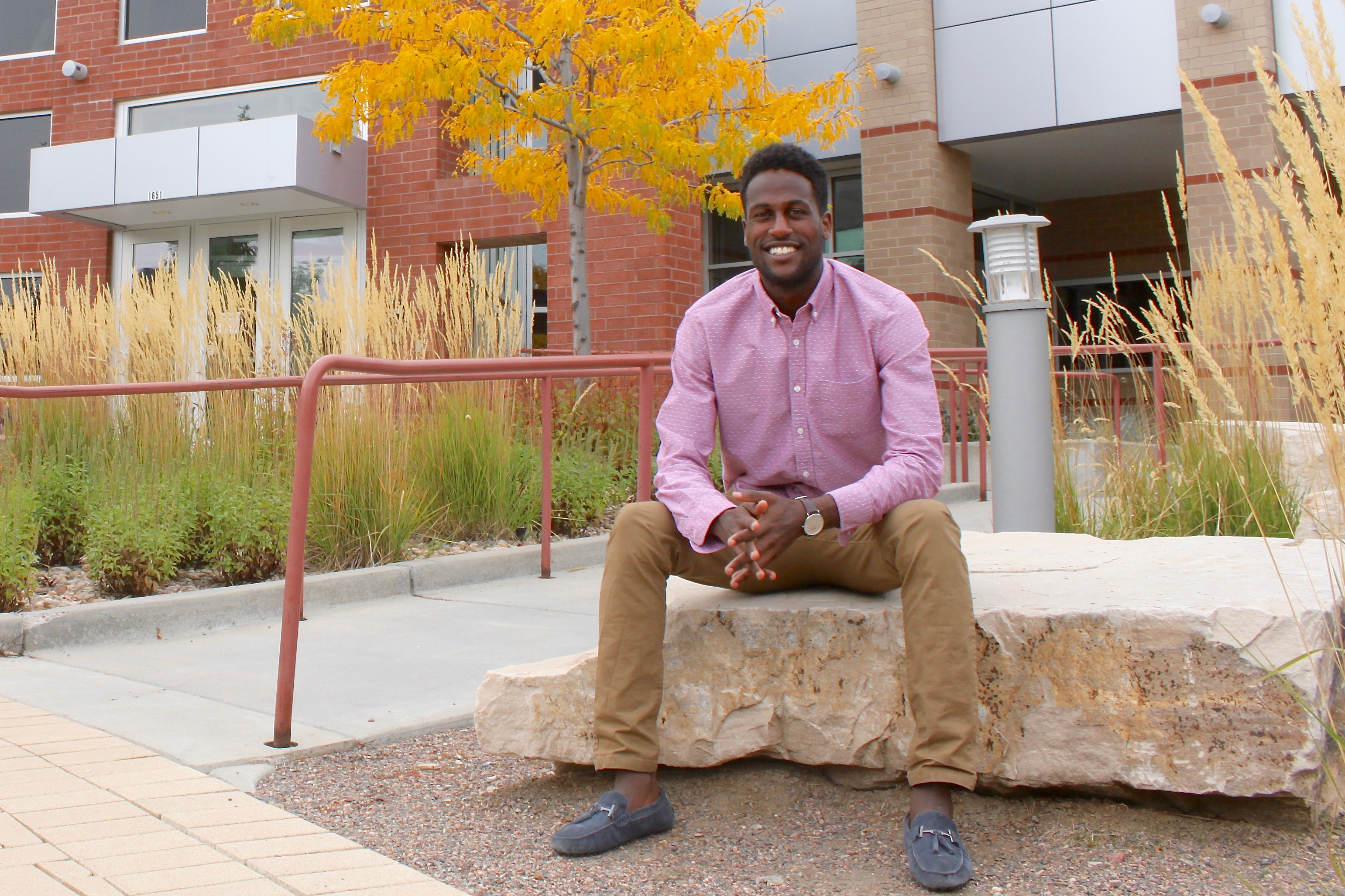 Ashanafe Geberkidane sits on a rock outside of a building on the Mines campus