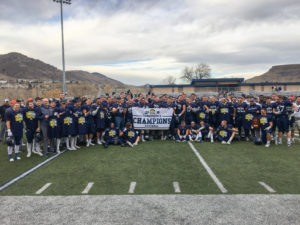 Mines football team holds championship banner