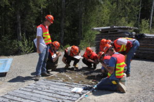 A group of students in hard hats work on a project at a mine site