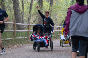 Women pumps her fist as she pushes a stroller during the Homecoming 5K