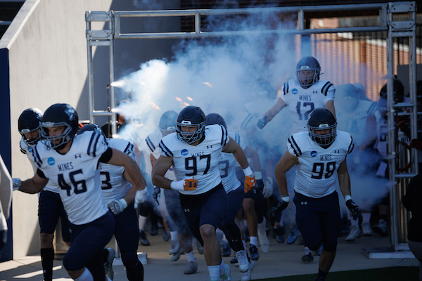 Mines football team running onto the field with smoke in the background