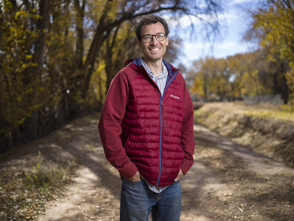 Kurtis Griess in a red jacket standing outside on a dirt path