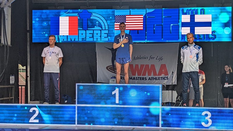 Three athletes stand on a tiered podium.