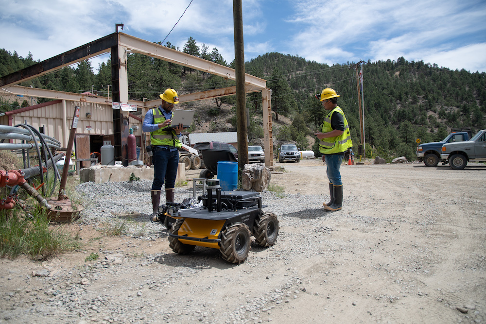 Two men operate a robot outside of a mine