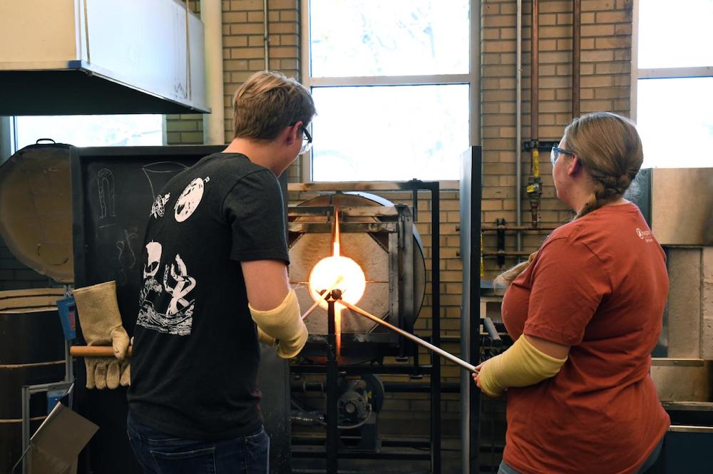 Two Mines students blowing glass on the Mines campus.