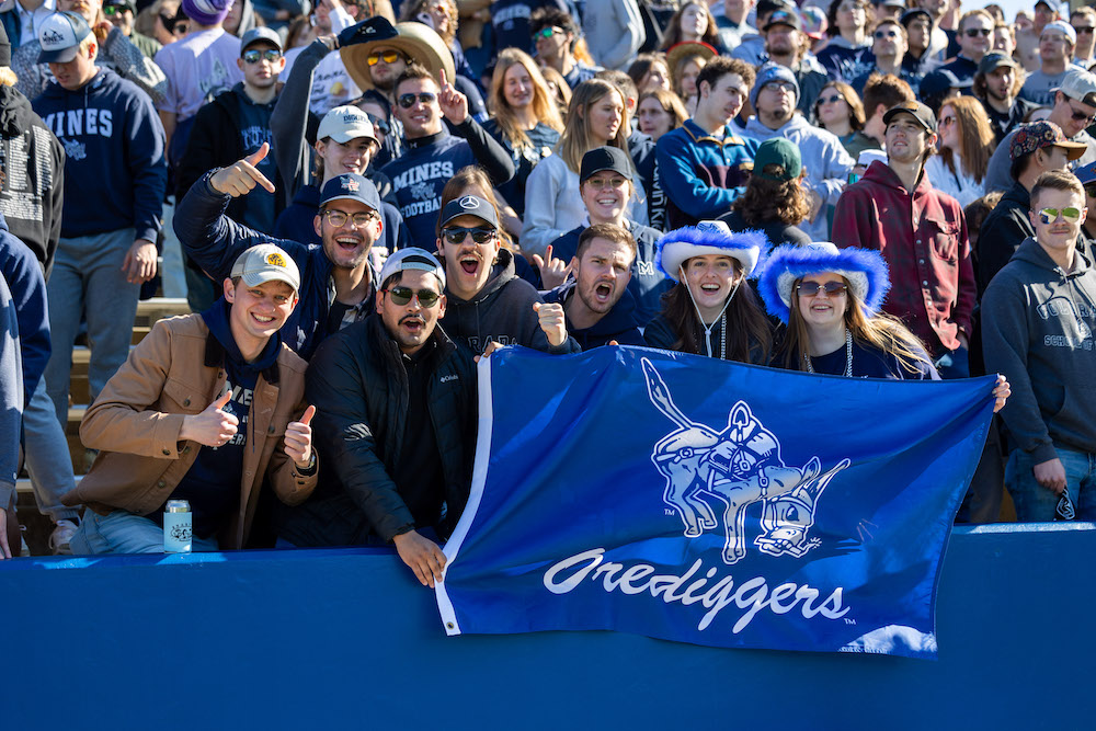 Mines students holding an Orediggers flag in the stands at a Mines football game