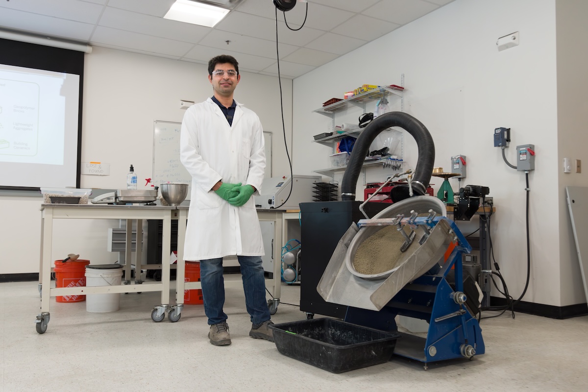 Reza Hedayat in a lab at Mines standing next to equipment used for pelletizing mine tailings
